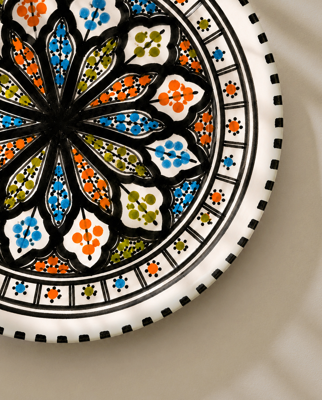 Gros plan du décor peint à la main d'une assiette plate en céramique artisanale de la collection Djerba.