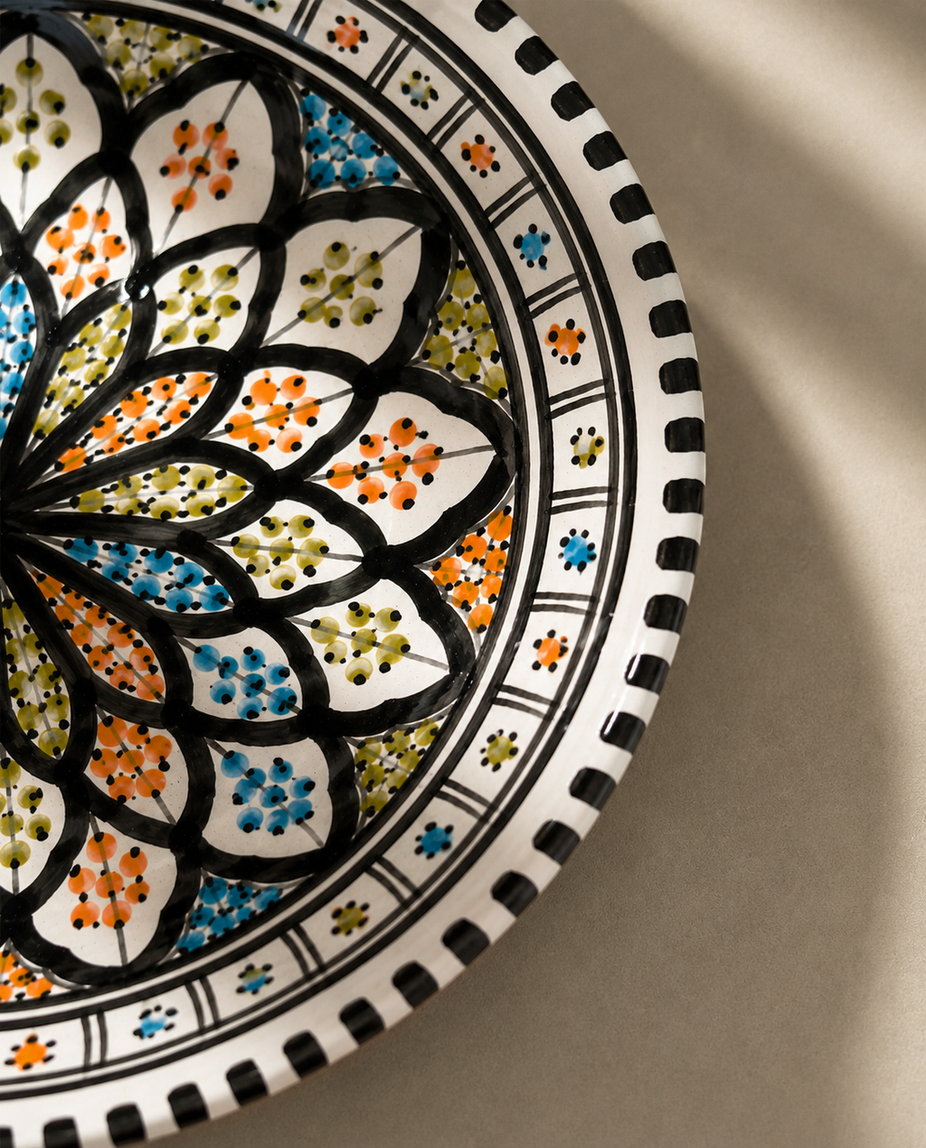 Gros plan du décor peint à la main d'un grand plat en céramique artisanale de la collection Djerba.